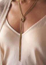 Close up of women wearing a gold chain knot necklace with silk top