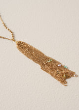 A close up of a long chain necklace with gold beads, finished with a multi-strand pendant, and colourful crystals