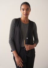 Model wearing a long chain necklace with gold beads, finished with a multi-strand pendant, and colourful crystals