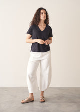 Woman wearing dark grey linen v-neck t-shirt and white jeans