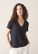 Woman wearing dark grey linen v-neck t-shirt and white jeans