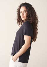 Woman wearing dark grey linen v-neck t-shirt and white jeans