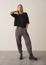 Woman wearing black short sleeve fine knit sweater and leopard print trousers
