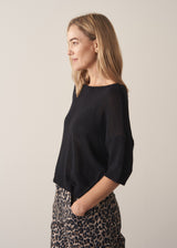 Woman wearing black short sleeve fine knit sweater and leopard print trousers