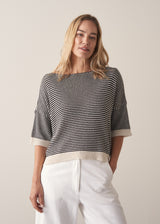 Woman wearing navy and white stripe light knitted sweater and white barrel leg jeans