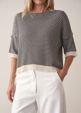 Woman wearing navy and white stripe light knitted sweater and white barrel leg jeans