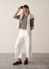 Woman wearing navy and white stripe light knitted sweater and white barrel leg jeans