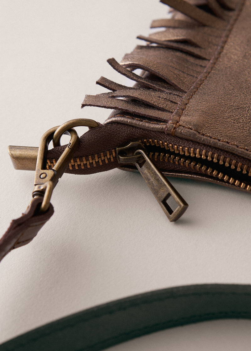 Bronze-coloured leather clutch bag with fringe details on a light gray background