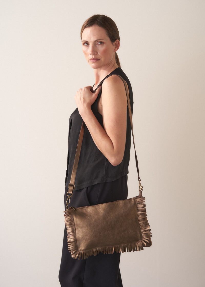 Bronze-coloured leather clutch bag with fringe details on a light gray background