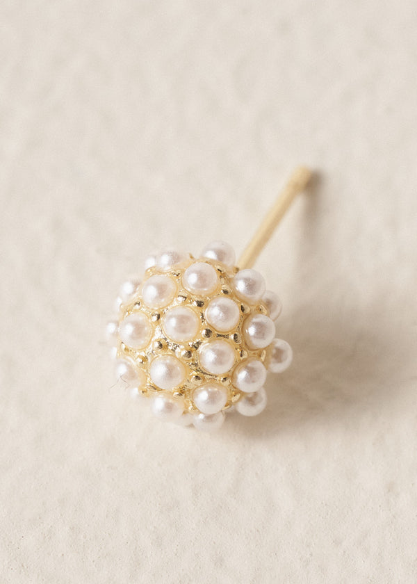 Gold stud earrings adorned with pearl clusters on a beige background