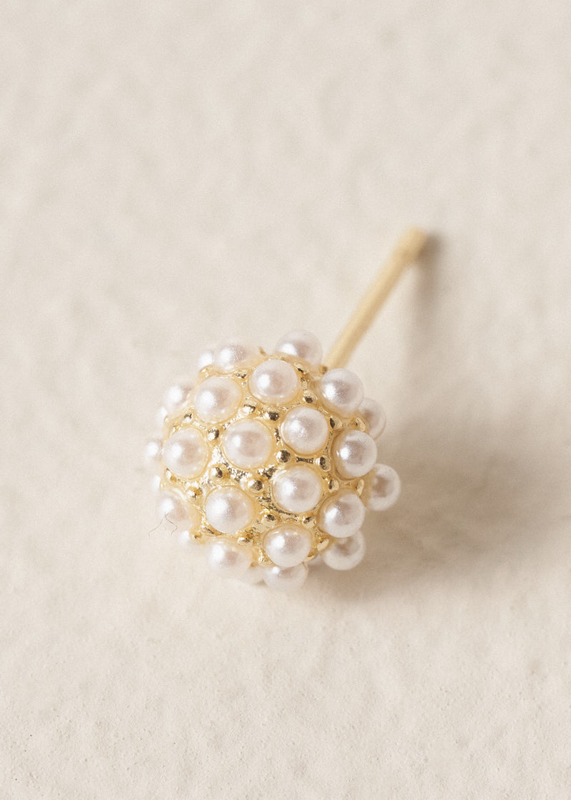 Gold stud earrings adorned with pearl clusters on a beige background
