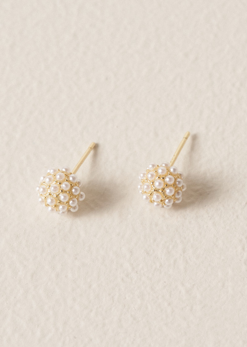 Pair of gold earrings  with pearl clusters on a beige background