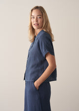 Woman wearing a navy blue short sleeve linen shirt and linen wide leg trousers