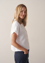 Woman wearing short sleeve white boxy linen shirt and dark navy trousers