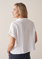 Woman wearing short sleeve white boxy linen shirt and dark navy trousers