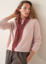 A woman wearing a pale pink boxy sweater with dark check barrel leg trousers