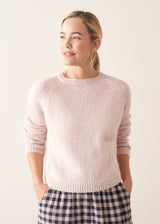 Woman wearing light blush pink boxy knitted sweater with checked barrel leg trousers