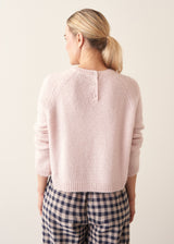 Woman wearing light blush pink boxy knitted sweater with checked barrel leg trousers