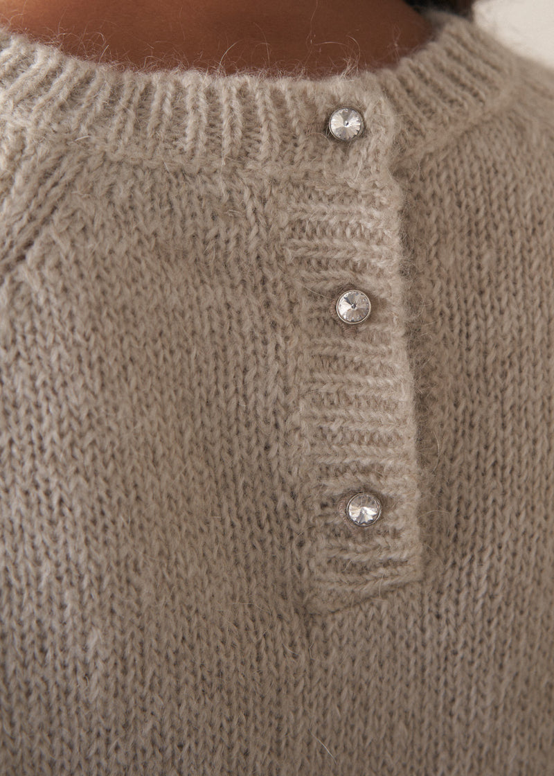 Close up of crystal button detail on a round neck oatmeal sweater