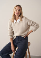 Woman wearing a beige boxy sweater with navy cotton trousers
