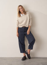 Woman wearing a beige boxy sweater with navy cotton trousers