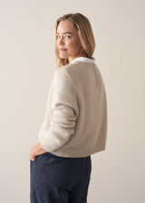 Woman wearing a beige boxy sweater with navy cotton trousers