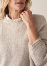 Woman wearing a beige boxy sweater with navy cotton trousers
