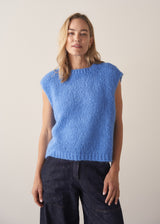 Woman wearing blue knitted sleeveless tank and dark blue jeans