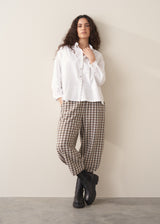 Model wearing neutral check barrel leg trousers and a white shirt
