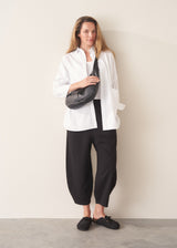 Woman wearing black jersey barrel leg trousers with a white vest and oversized white shirt