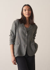 Woman wearing a khaki linen blazer and barrel leg linen trousers