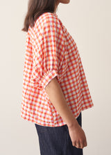 Woman wearing pink and orange gingham shirt with blue jeans