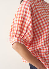 Woman wearing pink and orange gingham shirt with blue jeans