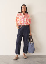 Woman wearing pink and orange gingham shirt with blue jeans