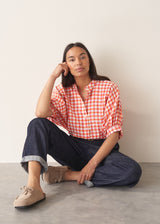 Woman wearing pink and orange gingham shirt with blue jeans