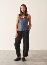 A woman wearing a midnight blue satin camisole with black trousers
