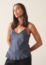 A woman wearing a midnight blue satin camisole with black trousers