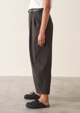 Woman wearing black check barrel leg trousers with a matching check jacket, white t-shirt and leather tote bag.