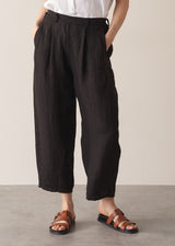 Woman wearing white linen shirt and black linen ankle length barrel leg trousers