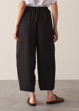 Woman wearing white linen shirt and black ankle length linen barrel leg trousers