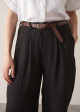 Woman wearing white linen shirt and black ankle length linen barrel leg trousers