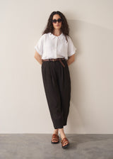Woman wearing white linen shirt and black linen ankle length barrel leg trousers