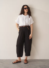 Woman wearing white linen shirt and black linen ankle length barrel leg trousers