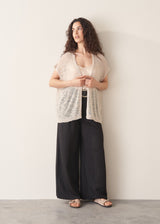 Woman wearing light beige cardigan with black trousers