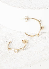 contemporary gold stud hoop earrings with crystal detail, on concrete backround