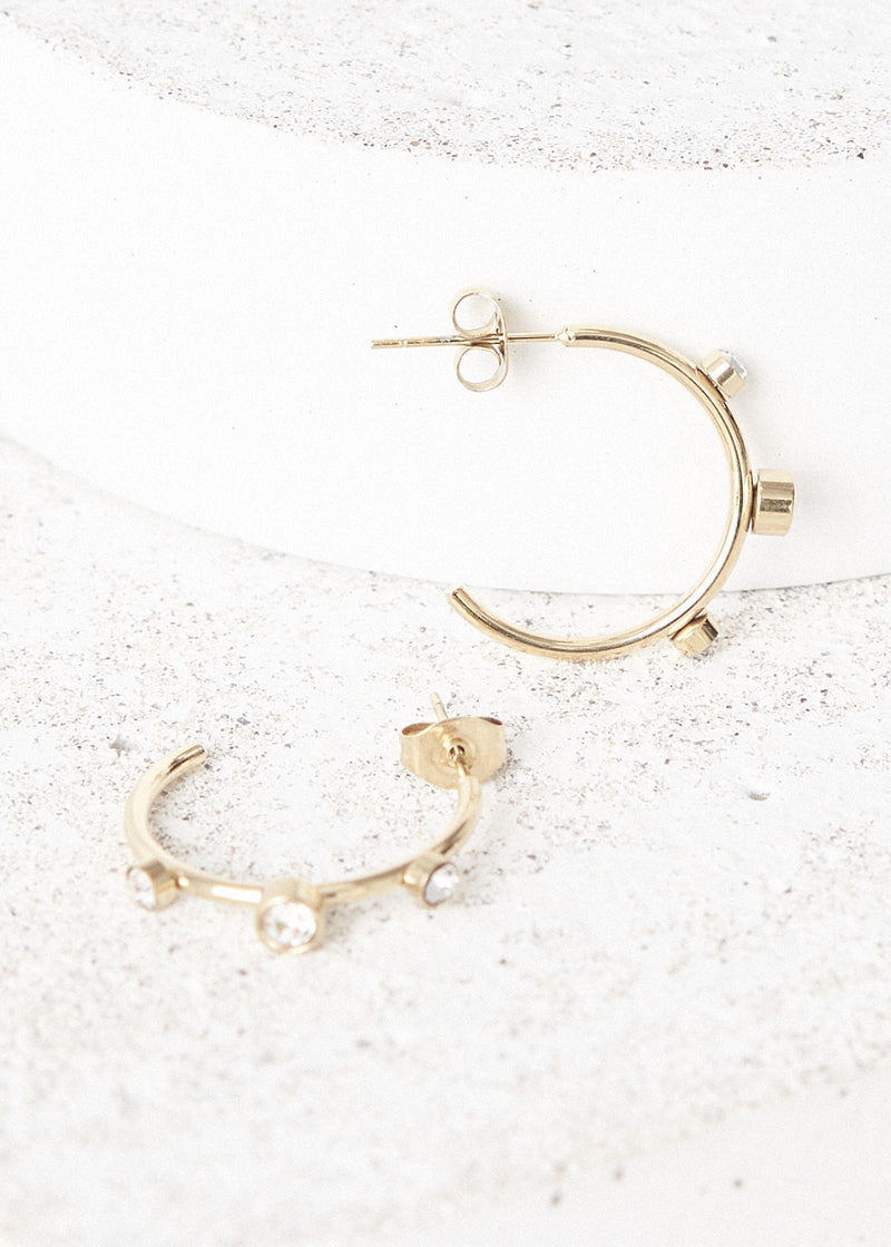 contemporary gold stud hoop earrings with crystal detail, on concrete backround