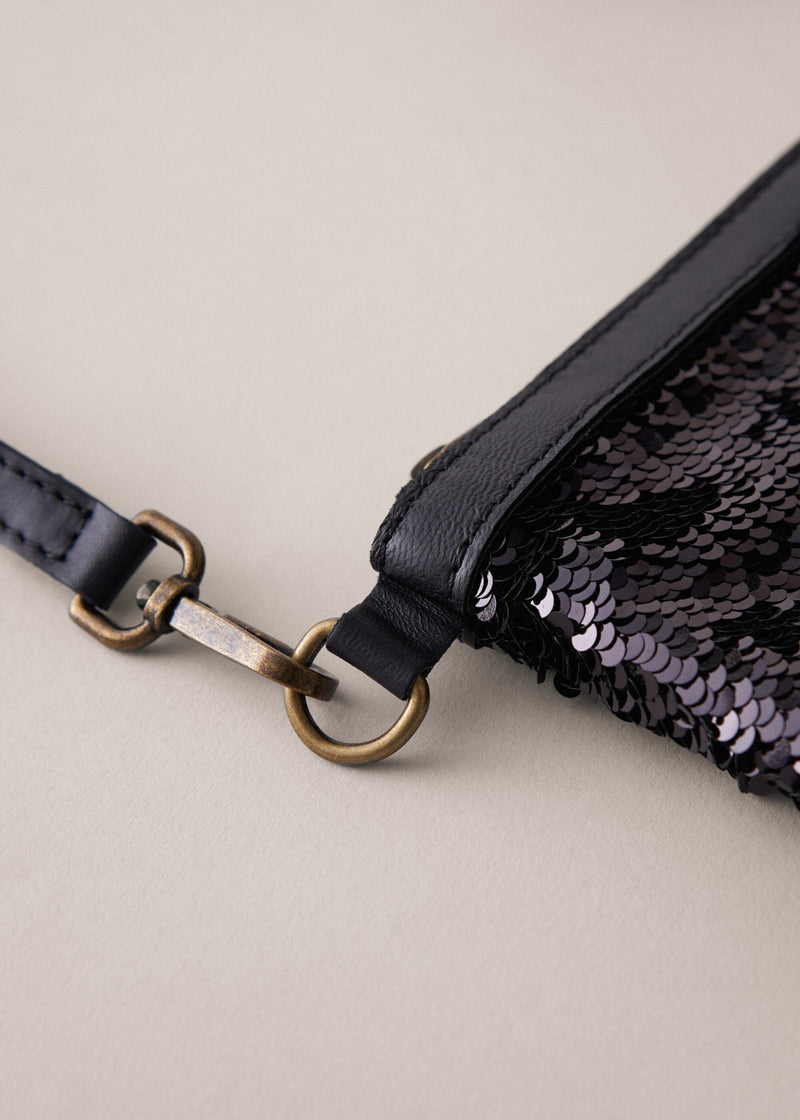 Black sequin clutch bag on a light beige background