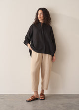 Woman wearing a black longline shirt with oatmeal linen trousers