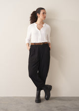 Woman wearing a white jersey top with black barrel leg trousers and chunky boots