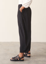 A woman wearing a white v-neck top and black slimtapered trousers.